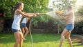 Beautiful image of happy laughing family with children having fun at hot summer day with water guns and garden hose Royalty Free Stock Photo