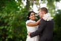 Beautiful indian bride and caucasian groom, in summer park. Happy young woman holding flowers. Young man smiling, Couple Royalty Free Stock Photo