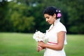 Beautiful indian bride in summer park. Happy young woman holding flowers. Girl after wedding, happiness and new family. Royalty Free Stock Photo