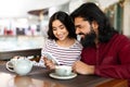 Beautiful indian couple with smartphone on date in coffee shop Royalty Free Stock Photo