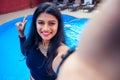 Beautiful indian woman toothy white smile selfie portrait on smartphone camera summer cafe by sea by the swimming pool Royalty Free Stock Photo