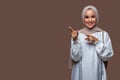 Beautiful indonesian woman wearing hijab is pointing to the left side with smiling