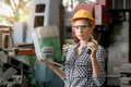 Beautiful industrial female engineer with helmet and safely glasses holding walkie talkie during using a laptop computer at Royalty Free Stock Photo