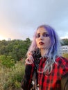 Beautiful informal girl with purple hair at sunset under a stormy sky.