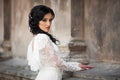 Beautiful innocent brunette bride in white dress posing near church wall Royalty Free Stock Photo