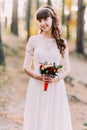 Beautiful innocent young brunette bride in gorgeous white dress with bouquet of flowers at forest Royalty Free Stock Photo