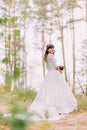 Beautiful innocent young brunette bride in gorgeous white dress stands on forest trail at sunny day Royalty Free Stock Photo