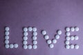 Beautiful inscription love made from white round smooth medical pills, vitamins, antibiotics and copy space Royalty Free Stock Photo