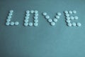 Beautiful inscription love made from white round smooth medical pills, vitamins, antibiotics and copy space on a bright blue Royalty Free Stock Photo