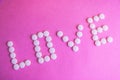 Beautiful inscription love made from white round smooth medical pills, vitamins, antibiotics and copy space on a bright purple Royalty Free Stock Photo