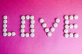 Beautiful inscription love made from white round smooth medical pills, vitamins, antibiotics and copy space on a bright purple Royalty Free Stock Photo