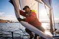 Beautiful inspiring shot of action adventure of sailor or captain on yacht or sailboat attaching big mainsail or