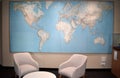 Beautiful interior with two modern armchairs a small white table and massive world map in background
