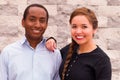 Beautiful interracial couple posing and smiling for camera, her hand on his shoulder Royalty Free Stock Photo