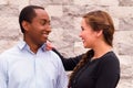 Beautiful interracial couple posing and smiling for camera, her hand on his shoulder looking into each others eyes Royalty Free Stock Photo