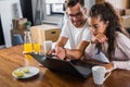 Beautiful interracial couple using laptop computer at home surfing the internet Royalty Free Stock Photo