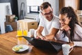 Beautiful interracial couple using laptop computer at home surfing the internet Royalty Free Stock Photo
