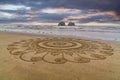 Intricate mandala sand art on a beach.