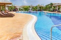 Beautiful inviting view of comfortable cozy curved swimming pool with people relaxing, swimming and enjoying their time