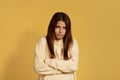 Beautiful irritated young caucasian woman in yellow hoodie holding her arms crossed, having angry and annnoyed face, expressing