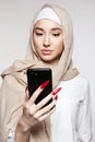 beautiful islamic young woman with smartphone. beauty girl in hijab looking at the screen