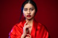 Beautiful Japanese Girl in Red Silk Kimono Dress. Asian Beauty Woman Face with Red Lips Makeup. Chinese Fashion Model showing Royalty Free Stock Photo