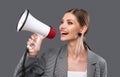 A beautiful joyful girl shouts into the loudspeaker on isolated pink background