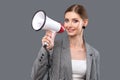 A beautiful joyful girl shouts into the loudspeaker on isolated pink background