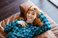 Beautiful joyful woman laying on brown sofa and laughing