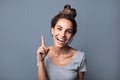 Beautiful joyful woman with a natural open smile pointing with index finger upwards over gray background Royalty Free Stock Photo