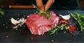 Beautiful juicy fresh meat steak on a table with salt, rosemary, garlic, and tomato on a black background, top view. Concept: fres