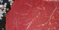 Beautiful juicy fresh meat steak on a table with salt, rosemary, garlic, and tomato on a black background, top view. Concept: fres