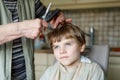 Beautiful kid boy with blond hairs getting his first haircut. Royalty Free Stock Photo