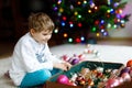 Beautiful kid boy and colorful vintage xmas toys and balls in old suitcase. Little child, school boy in festive clothes Royalty Free Stock Photo