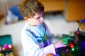 Beautiful kid boy and colorful vintage xmas toys and balls in old suitcase. Little child, school boy in festive clothes Royalty Free Stock Photo