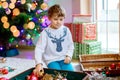Beautiful kid boy and colorful vintage xmas toys and balls. Child decorating Christmas tree Royalty Free Stock Photo