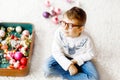 Beautiful kid boy and colorful vintage xmas toys and balls in old suitcase. Little child, school boy in festive clothes Royalty Free Stock Photo