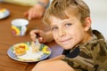 Beautiful kid boy eating apple pie in restaurant on vacations. Happy healthy child in an outdoor cafe in summer time Royalty Free Stock Photo