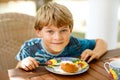 Beautiful kid boy eating apple pie in restaurant on vacations. Happy healthy child in an outdoor cafe in summer time Royalty Free Stock Photo