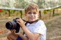 Beautiful kid boy with glasses making pictures by using digital professional camera. Little child learning to be Royalty Free Stock Photo