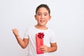 Beautiful kid boy holding birthday gift standing over isolated white background pointing and showing with thumb up to the side Royalty Free Stock Photo