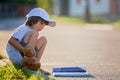 Beautiful kid boy, reading a book on the street, sitting down wi Royalty Free Stock Photo