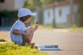 Beautiful kid boy, reading a book on the street, sitting down wi Royalty Free Stock Photo