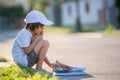 Beautiful kid boy, reading a book on the street, sitting down wi Royalty Free Stock Photo