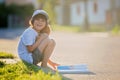 Beautiful kid boy, reading a book on the street, sitting down wi Royalty Free Stock Photo