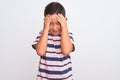 Beautiful kid boy wearing casual striped t-shirt standing over isolated white background with hand on head for pain in head Royalty Free Stock Photo