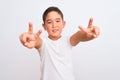 Beautiful kid boy wearing casual t-shirt standing over isolated white background smiling looking to the camera showing fingers Royalty Free Stock Photo