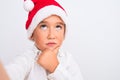 Beautiful kid boy wearing Christmas Santa hat make selfie over isolated white background serious face thinking about question,