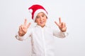 Beautiful kid boy wearing Christmas Santa hat standing over isolated white background smiling looking to the camera showing Royalty Free Stock Photo