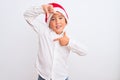 Beautiful kid boy wearing Christmas Santa hat standing over isolated white background smiling making frame with hands and fingers Royalty Free Stock Photo